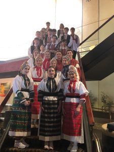 (English) Klub Stepinac in folk costumes posed on the hotel staircase, girls in front and boys behind.